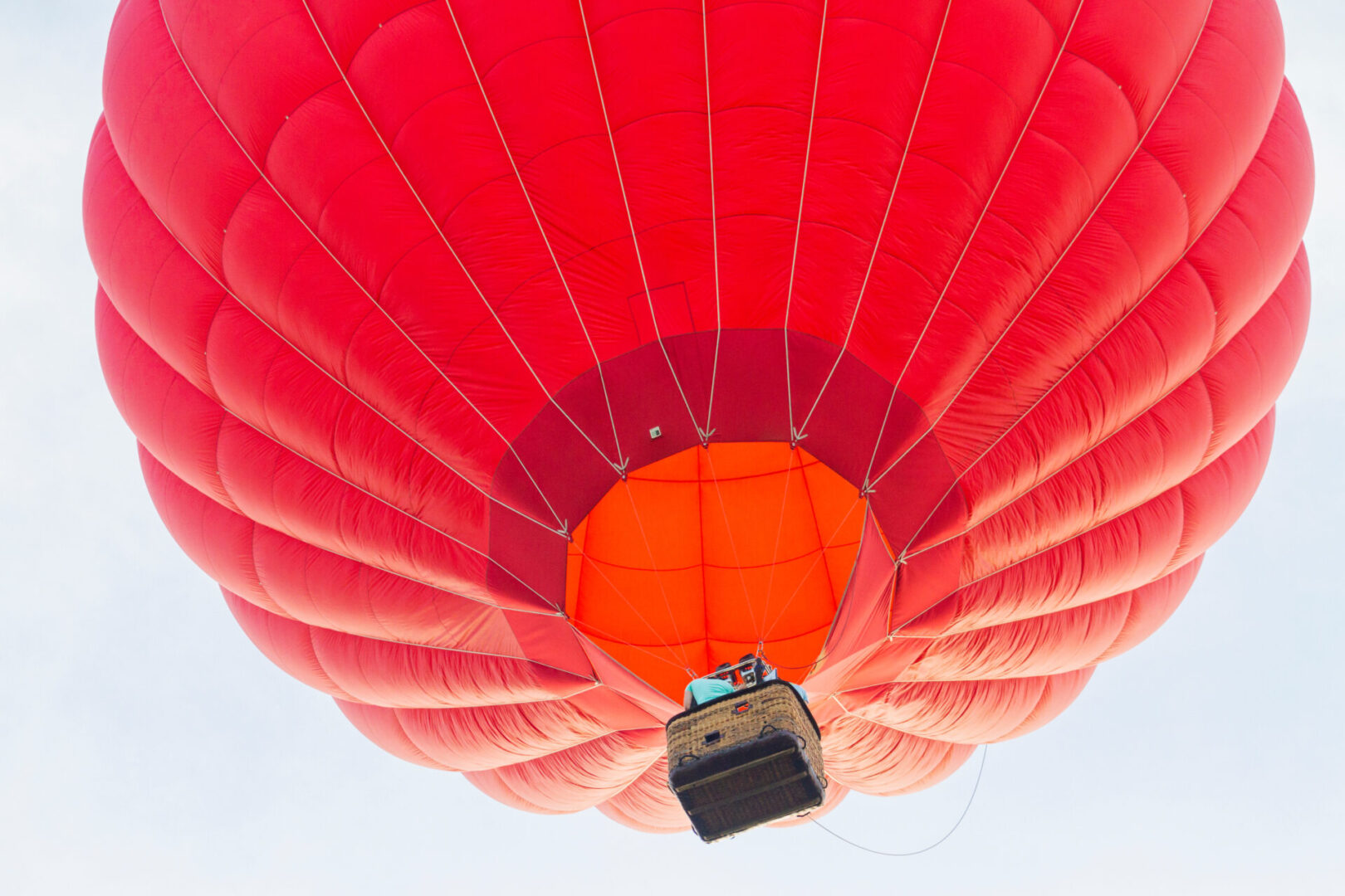 Close-up of a red hot air balloon ascending with a basket.