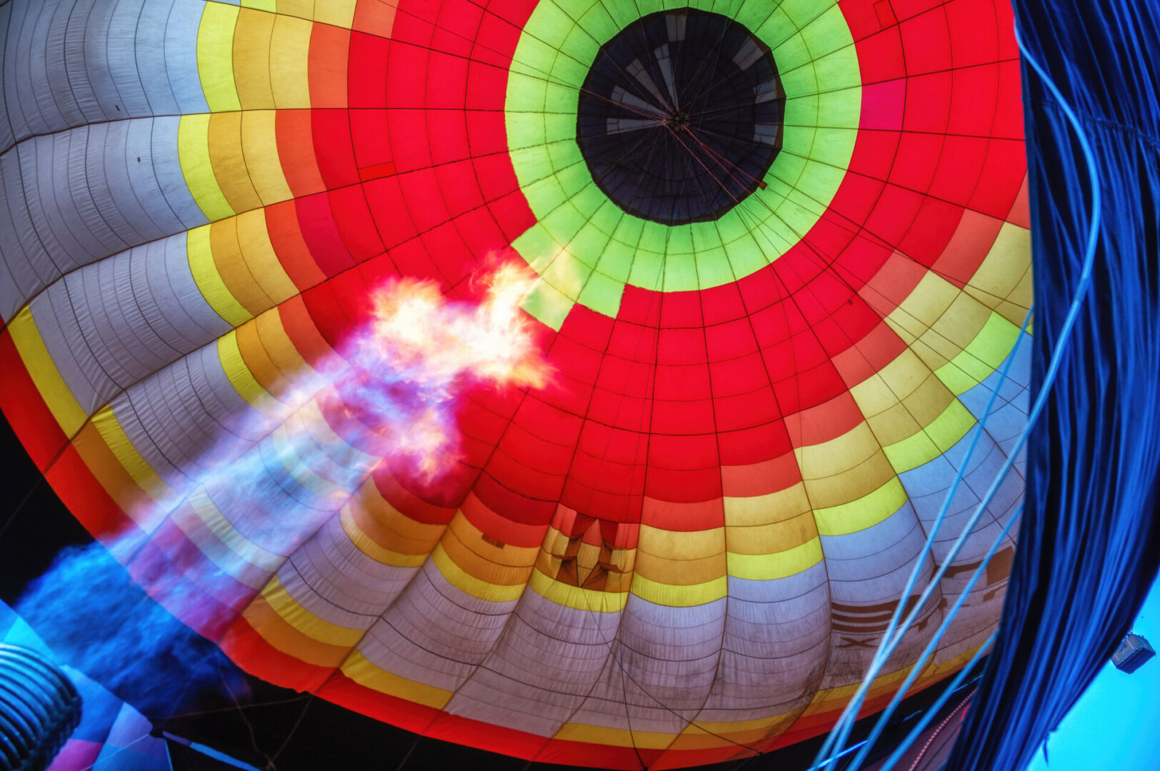 Inside view of a colorful hot air balloon being inflated with a flame.